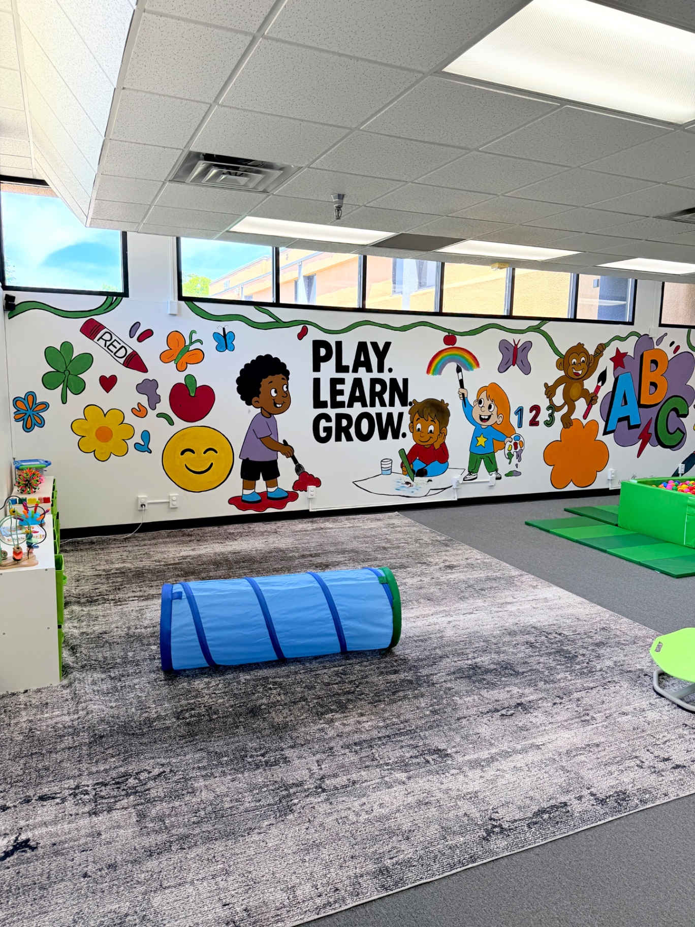 Spectrum Roots playroom with a colorful Play. Learn. Grow. mural and sensory play equipment